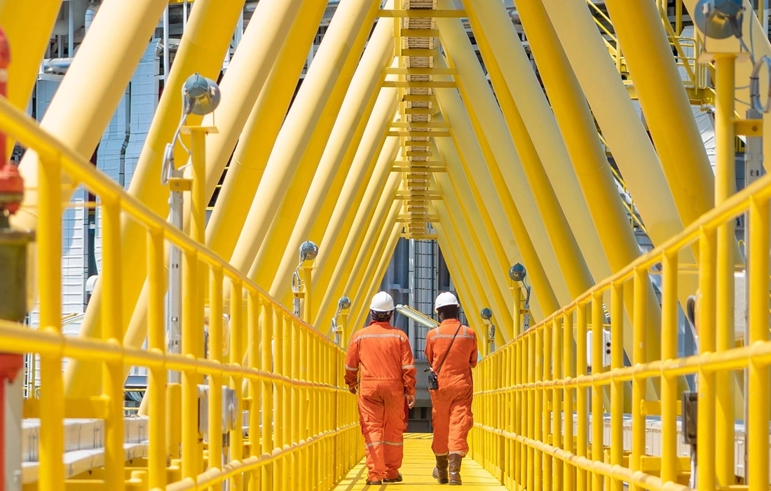 two workers walking down a long industrial pathway